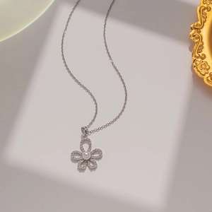 Detailed close-up of a silver flower necklace featuring crystal petals and a central pearl
