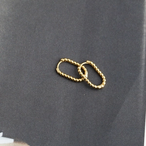 Close-up of golden U-shaped S925 silver hoop earrings with a unique beaded texture finish