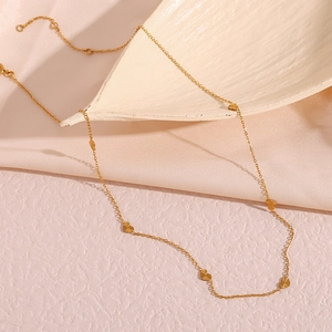 Close-up of gold stainless steel necklace featuring textured heart charms on pink silk