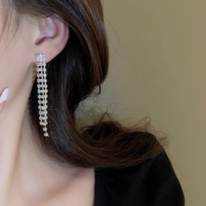 Close-up of elegant silver tassel drop earrings with sparkling rhinestones on model