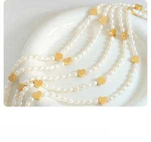 Macro shot of freshwater pearl necklace featuring gold heart-shaped metal connectors