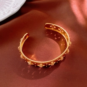 Detailed macro view of a vintage gold open cuff bracelet with star flower engravings
