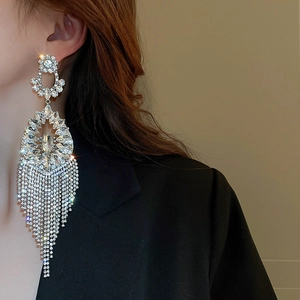 Close-up of long silver fringe earrings with flower design and sparkling rhinestones