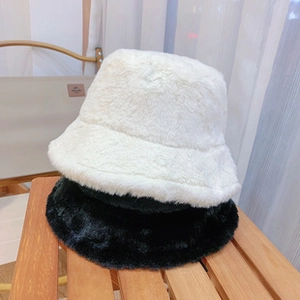 Detail view of soft plush fisherman hats in black and white colors on a wooden chair