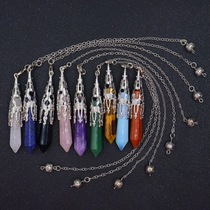 Macro detail of various gemstone pendulums with hollow metal caps and silver chains
