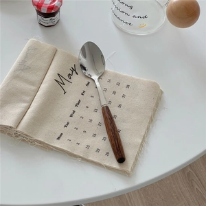 Detail of vintage wooden handle spoon with polished metal head on a white minimalist table