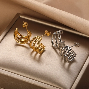 Macro view of gold and silver minimalist triple-layered hoop earrings on silk