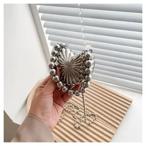 Close-up of heart-shaped silver metal evening bag with pearl bead handle and chain