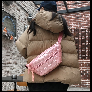 Pink quilted puffer fanny pack with braided knot strap worn by a model in street style