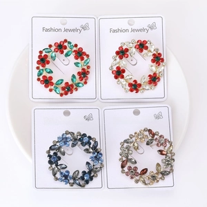 Detailed macro view of four rhinestone flower wreath brooches displayed on a ceramic tray