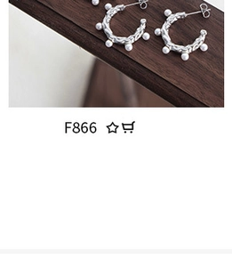 Detailed view of silver textured earrings set with small pearls on dark wood