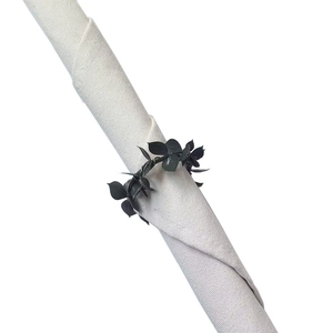 Macro shot of dark green leaf napkin ring around a beige linen cloth on white background