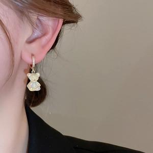 Détail d'une boucle d'oreille en or avec zircon et pendentif ours en résine coloré