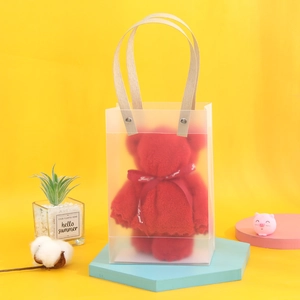 Detail of red bear-shaped towel in transparent gift bag on a blue display stand