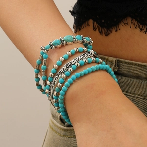 Detail of bohemian layered turquoise beaded bracelets set with vintage silver charms