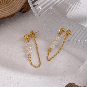 Detailed macro view of natural freshwater pearl tassel earrings with gold sphere studs