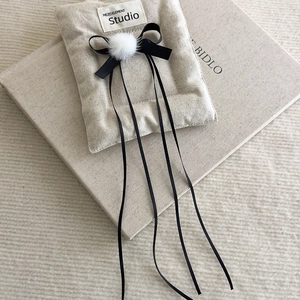 Close-up of ballet-style hair clip with black ribbon bow and soft white faux fur pompom