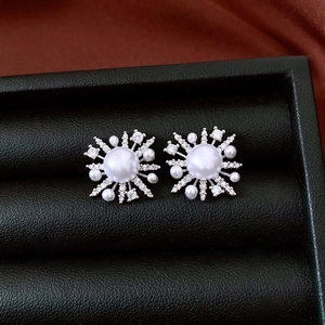 Macro shot of snowflake pearl earrings with clear zircons in a black velvet jewelry box