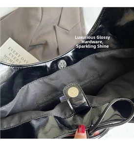 Detail view of glossy black patent leather bag featuring magnetic buckle and inner zip pocket