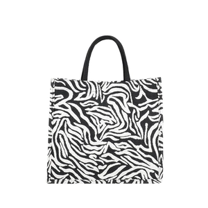 Minimalist zebra print tote bag with black handles and woven fabric on white background
