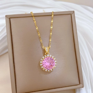 Macro shot of gold-plated twisted chain necklace with a pink zirconia round pendant
