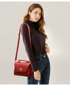 Detail of red leather crossbody bag with vintage gold turn-lock on female model