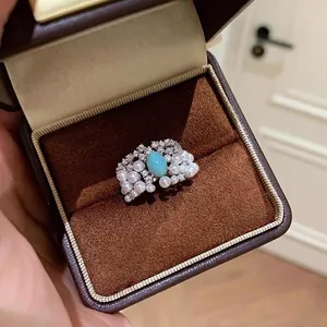 Detail of vintage square ring with sky blue stone, pearls, and zircons in a jewelry box