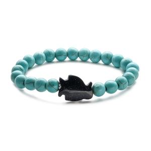 Detailed view of turquoise bead bracelet featuring a dark blue sparkling fish charm