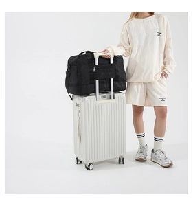 Detail showing black waterproof travel bag with sleeve attached to a suitcase handle