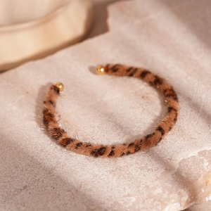 Macro shot of leopard print faux fur open cuff bracelet on stone base with gold accents