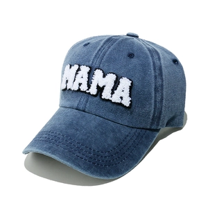 Detailed view of white towel embroidery MAMA letters on washed denim baseball cap