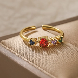 Close-up of gold plated ring with four colorful round zircons on a beige jewelry display box
