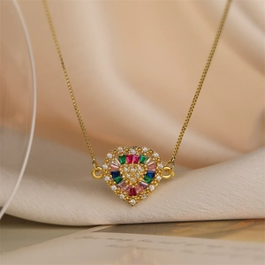Macro shot of gold heart pendant necklace with colorful zircons on beige silk fabric