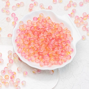 Macro shot of pink and yellow frosted gradient glass beads in a white shell bowl