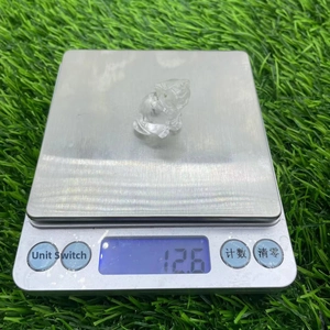 Cute 1.2 inch natural clear crystal cat figurine being weighed on a digital scale
