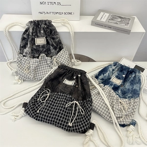 Three color variants of checkered drawstring backpacks with tie-dye patterns and thick ropes