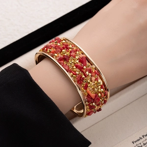 Detail of bohemian open cuff bracelet with red crushed stones and gold beads on model