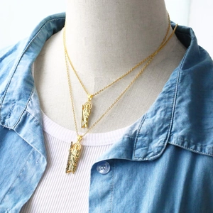 Detail of 18K gold plated Saint Jude pendants with green zircons on a model