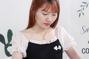 Close-up of a elegant golden necklace with a round sparkling crystal pendant on model