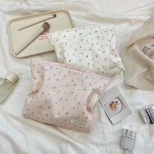 Detail of floral fabric makeup bags with blue flower patterns on a soft beige background