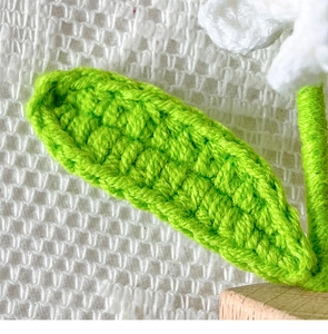 Macro shot of handmade knitted green leaf texture and white flower petal detail