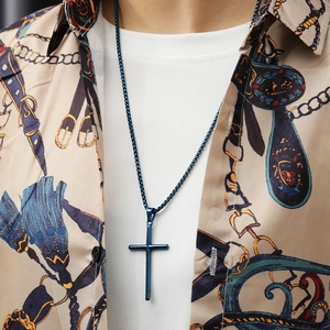 Detailed view of a minimalist blue cross pendant on a thin chain worn by a male model