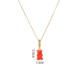 Detail view of a gold chain necklace with a vivid orange gummy bear pendant and gems