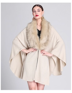 Detail of a beige knit shawl cape featuring a voluminous faux fox fur collar for winter