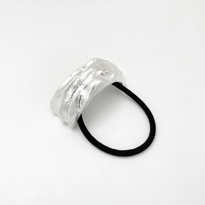 Close-up of black elastic hair tie with a silver U-shaped metal buckle on white background