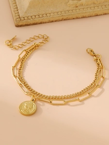 Détail d'un bracelet double couche en or avec pendentif pièce Reine Elizabeth et chaîne trombone