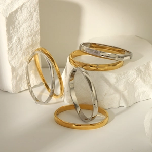 Polished 18K gold and silver minimalist bangles with hinge closure on stone pedestal