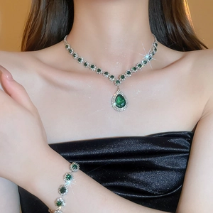 Detail of luxury teardrop necklace and bracelet set with emerald green stones and diamonds