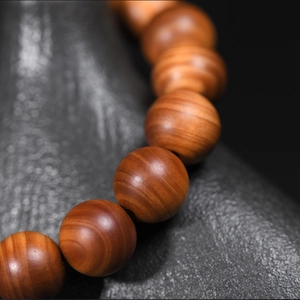 Aged cypress wood prayer beads in natural brown-red finish with oily wood grain texture