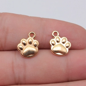 Pair of gold-plated paw print pendants held on fingertips to show 14x12mm size